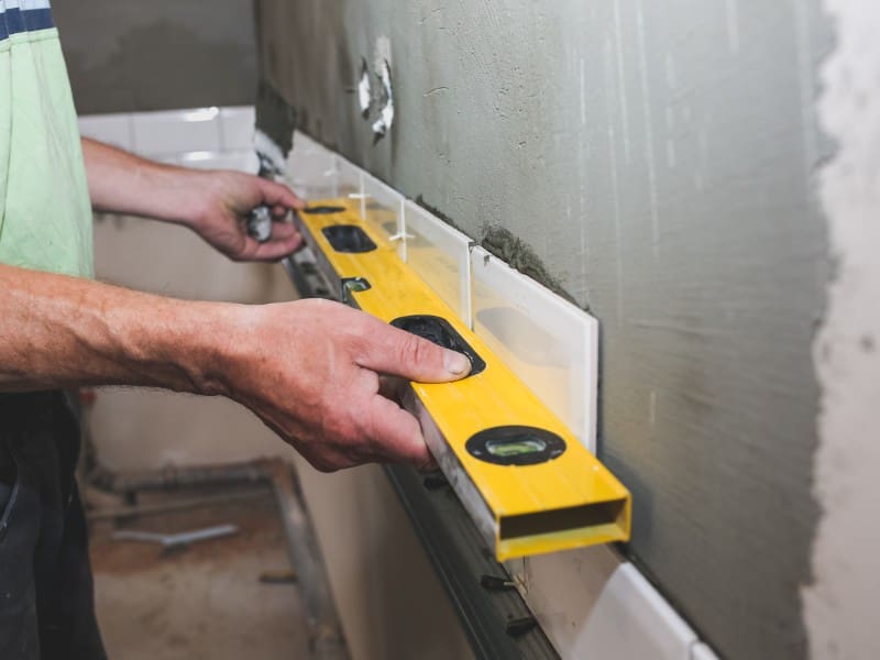 Person leveling tiles with a spirit level.