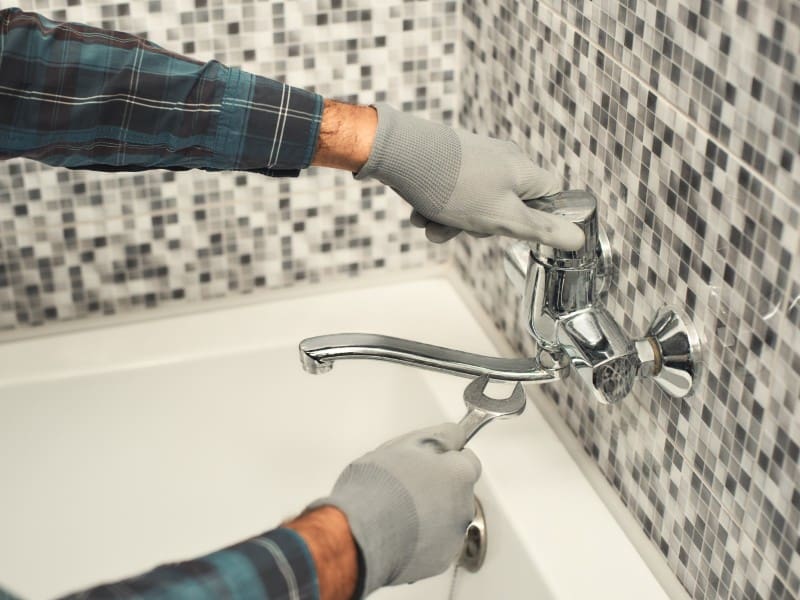 Plumber repairing bathroom faucet.