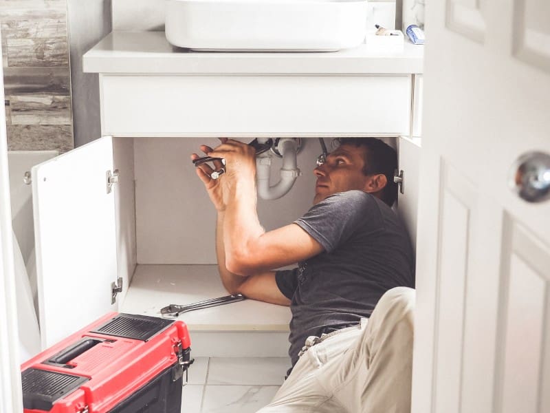 Plumber repairing sink under cabinet.