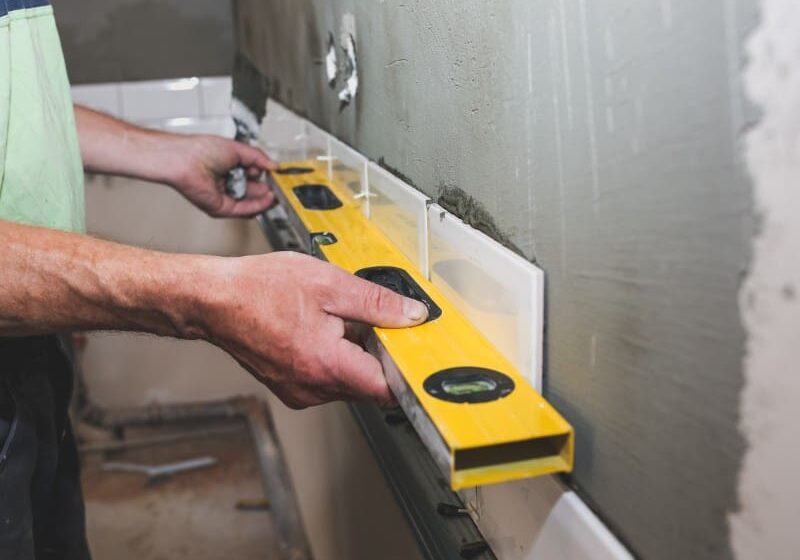 Person leveling tiles with a spirit level.